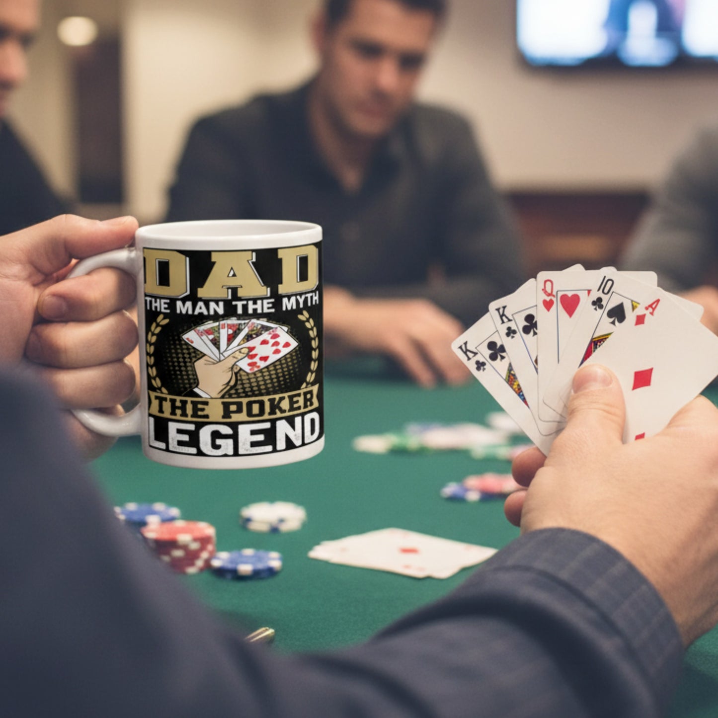 Poker player holding a Dad The Man The Myth The Poker Legend coffee mug during a poker game, featuring a royal flush card design, poker chips, playing cards, and casino night atmosphere.