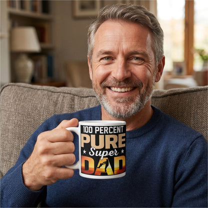 Man holding a 100 Percent Pure Super Dad coffee mug with a father-and-child silhouette against a sunset background.