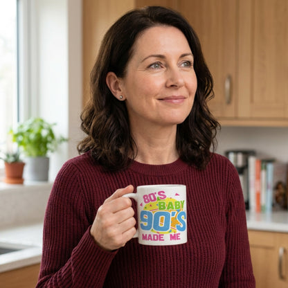 Woman holding an 80's Baby 90's Made Me coffee mug with colorful retro design in a bright kitchen