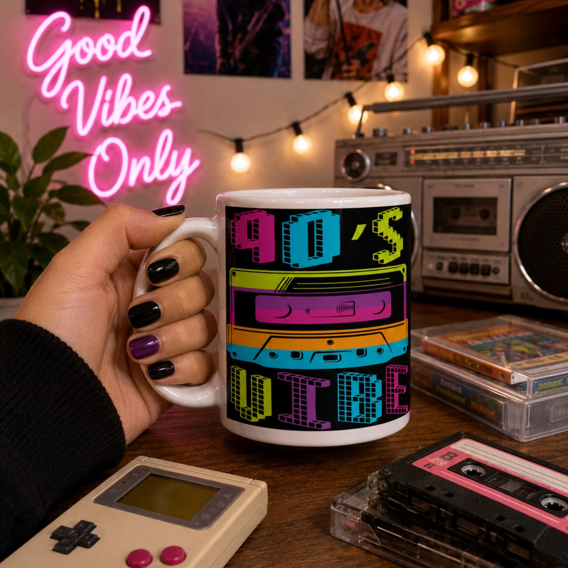 Lifestyle mockup of a colourful 90s Vibe coffee mug with a vibrant retro cassette tape design, held in a retro-inspired room featuring a vintage boombox, cassette tapes, Game Boy, and neon Good Vibes Only sign.