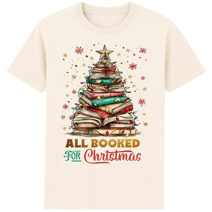 Naturel colour All Booked For Christmas T-shirt featuring a Christmas tree made from stacked books with festive lights and a star, a Christmas book lover shirt and Christmas reading tee for readers, librarians, and bookworms.
