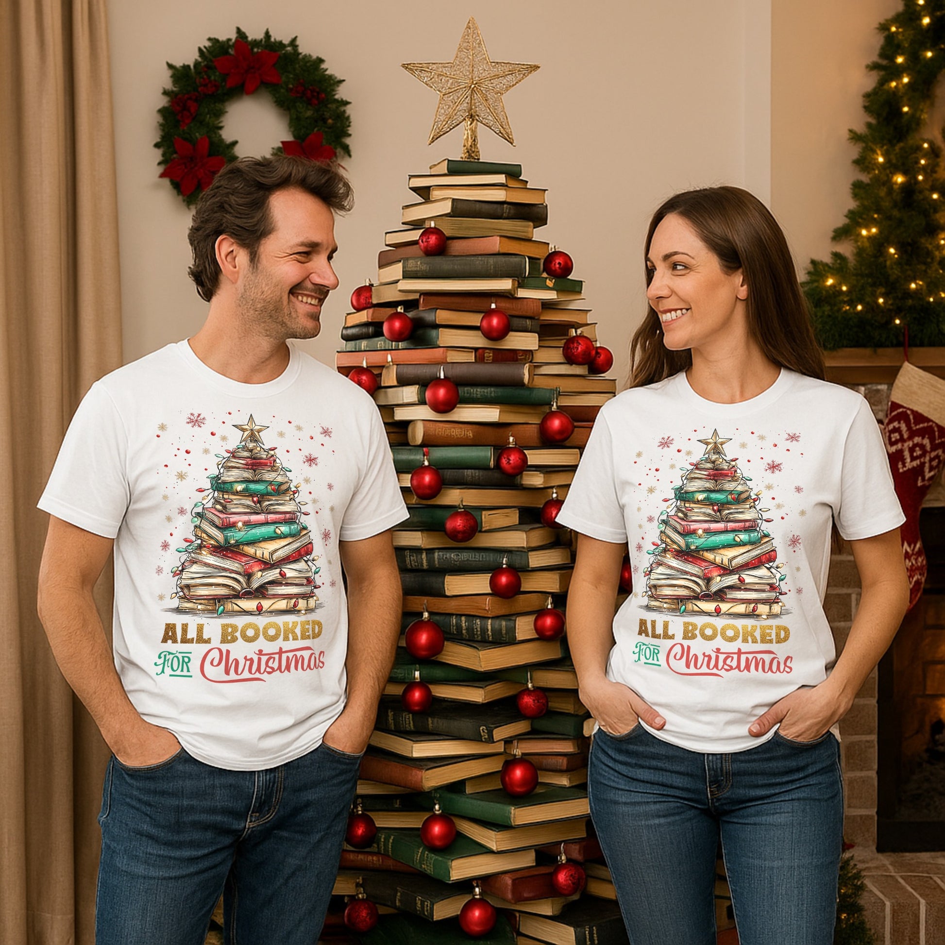 Two people wearing 'All Booked for Christmas' t-shirts in front of a book Christmas tree.