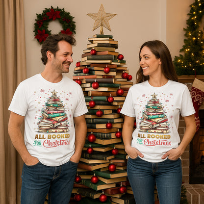 Two people wearing 'All Booked for Christmas' t-shirts in front of a book Christmas tree.
