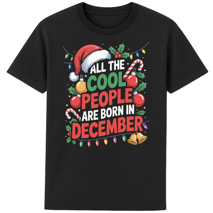 All The Cool People Are Born In December T-Shirt featuring festive Christmas typography with Santa hat, candy canes, holly, baubles, and colourful Christmas lights on a black unisex tee, perfect funny December birthday shirt and Christmas birthday gift.