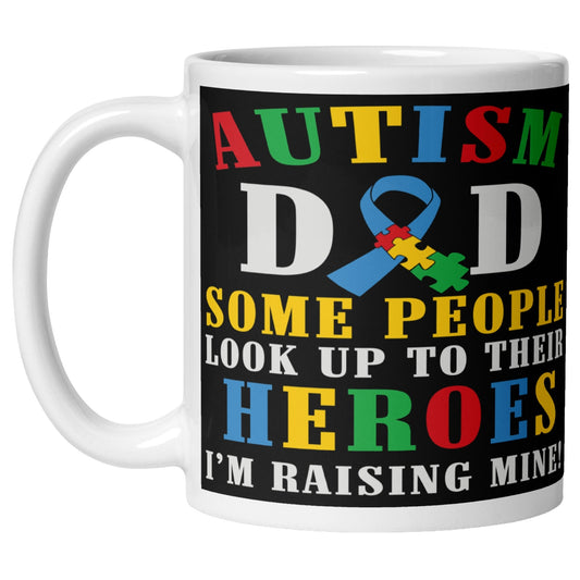 Autism Dad coffee mug featuring a colourful autism awareness ribbon and the quote “Some People Look Up To Their Heroes I'm Raising Mine”, celebrating autism awareness, support, and proud fathers.