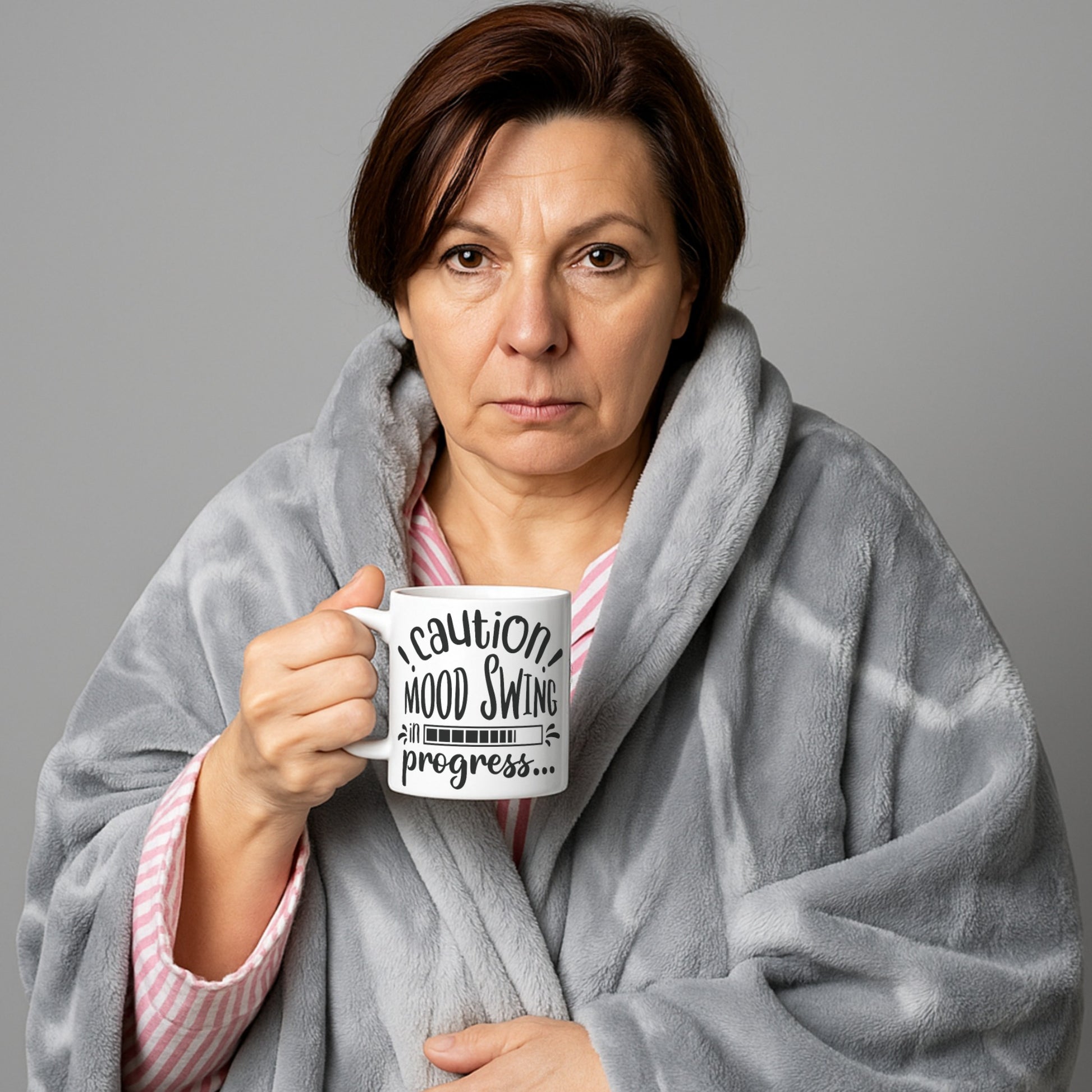 Woman wrapped in a blanket holding a mug with text that reads “Caution! Mood Swing in Progress…” — a humorous gift idea, especially relatable for menopause mood swings.