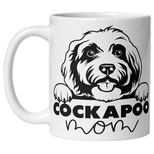White ceramic mug with a cute cartoon Cockapoo face and the words "Cockapoo Mom" printed on the front, perfect for dog lovers and pet parents.