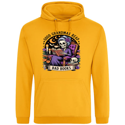 Gold colour Good Grandmas Read Bad Books Hoodie featuring a spooky cute skeleton grandma reading in a cosy armchair with candles and flowers, funny grandma hoodie for book lovers and gothic readers.