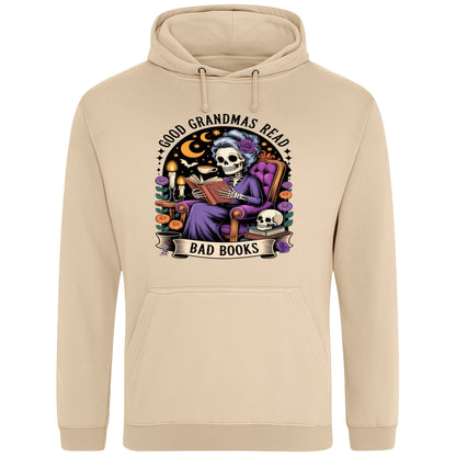 Nude colour Good Grandmas Read Bad Books Hoodie featuring a spooky cute skeleton grandma reading in a cosy armchair with candles and flowers, funny grandma hoodie for book lovers and gothic readers.