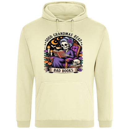 Vanilla milkshake colour Good Grandmas Read Bad Books Hoodie featuring a spooky cute skeleton grandma reading in a cosy armchair with candles and flowers, funny grandma hoodie for book lovers and gothic readers.