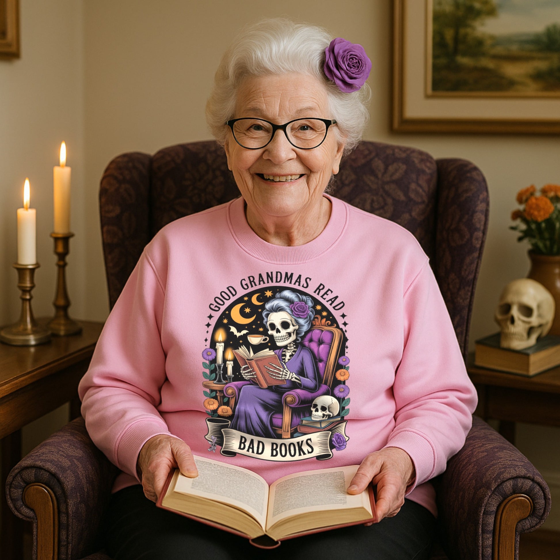 Smiling grandma wearing the Good Grandmas Read Bad Books Sweatshirt while reading a book in a cosy armchair with candles, flowers, and gothic décor, funny grandma sweatshirt for book lovers and gothic book lovers.
