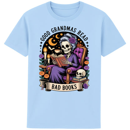 Blue Soul colour Good Grandmas Read Bad Books T-Shirt featuring a spooky cute skeleton grandma reading in a cosy armchair with candles and flowers, funny grandma t shirt for book lovers and gothic book lovers.