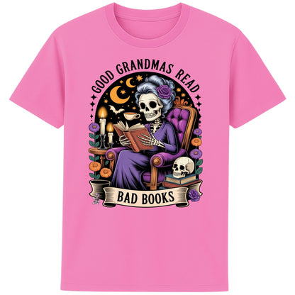Bubble pink colour Good Grandmas Read Bad Books T-Shirt featuring a spooky cute skeleton grandma reading in a cosy armchair with candles and flowers, funny grandma t shirt for book lovers and gothic book lovers.