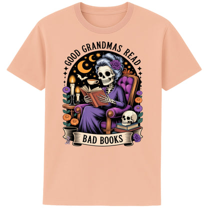 Fraiche peche colour Good Grandmas Read Bad Books T-Shirt featuring a spooky cute skeleton grandma reading in a cosy armchair with candles and flowers, funny grandma t shirt for book lovers and gothic book lovers.