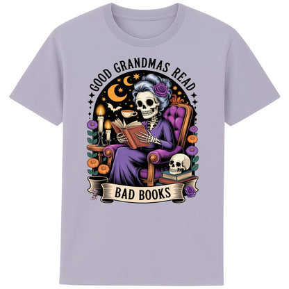 Lavender colour Good Grandmas Read Bad Books T-Shirt featuring a spooky cute skeleton grandma reading in a cosy armchair with candles and flowers, funny grandma t shirt for book lovers and gothic book lovers.