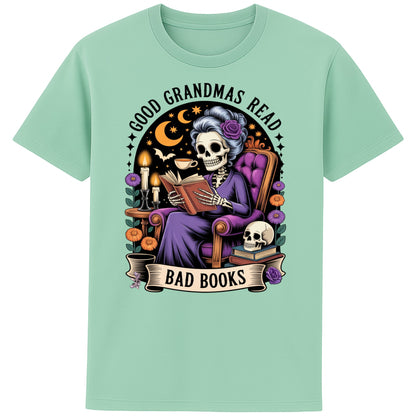Misty Jade colour Good Grandmas Read Bad Books T-Shirt featuring a spooky cute skeleton grandma reading in a cosy armchair with candles and flowers, funny grandma t shirt for book lovers and gothic book lovers.