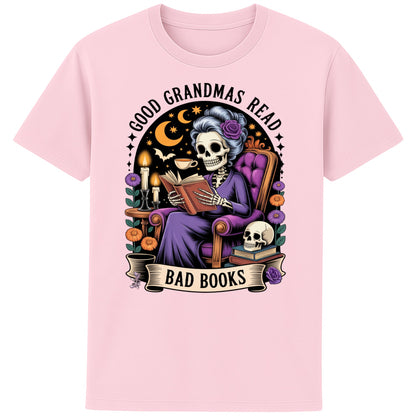 Pink Good Grandmas Read Bad Books T-Shirt featuring a spooky cute skeleton grandma reading in a cosy armchair with candles and flowers, funny grandma t shirt for book lovers and gothic book lovers.