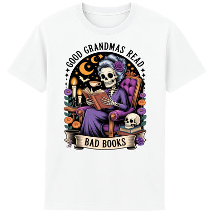 White Good Grandmas Read Bad Books T-Shirt featuring a spooky cute skeleton grandma reading in a cosy armchair with candles and flowers, funny grandma t shirt for book lovers and gothic book lovers.