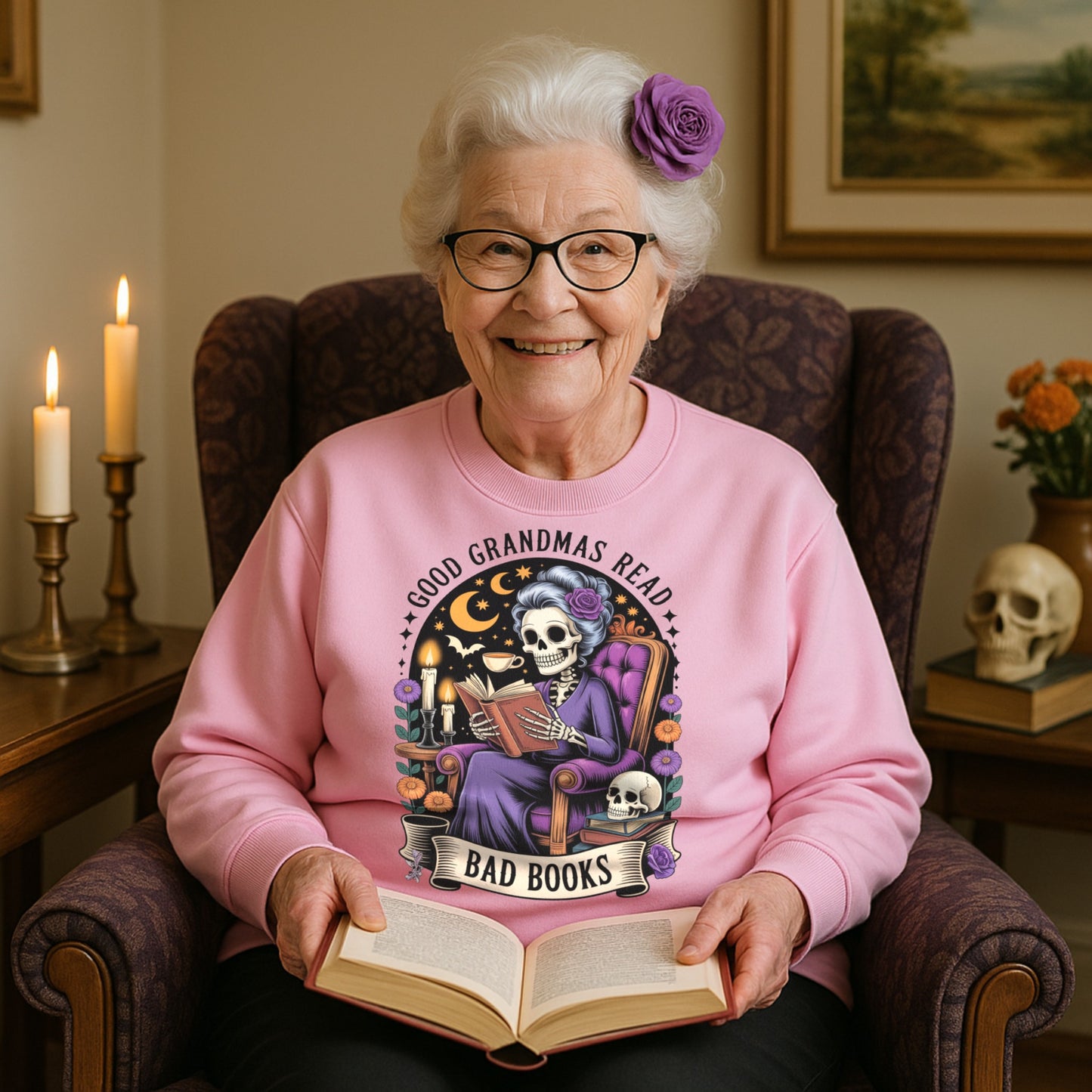 Woman wearing a pink sweatshirt . with gothic skeleton grandma Good Grandmas Read Bad Books design ideal gift for bookworms and quirky grandmas. with a book-themed design, sitting in a chair holding an open book