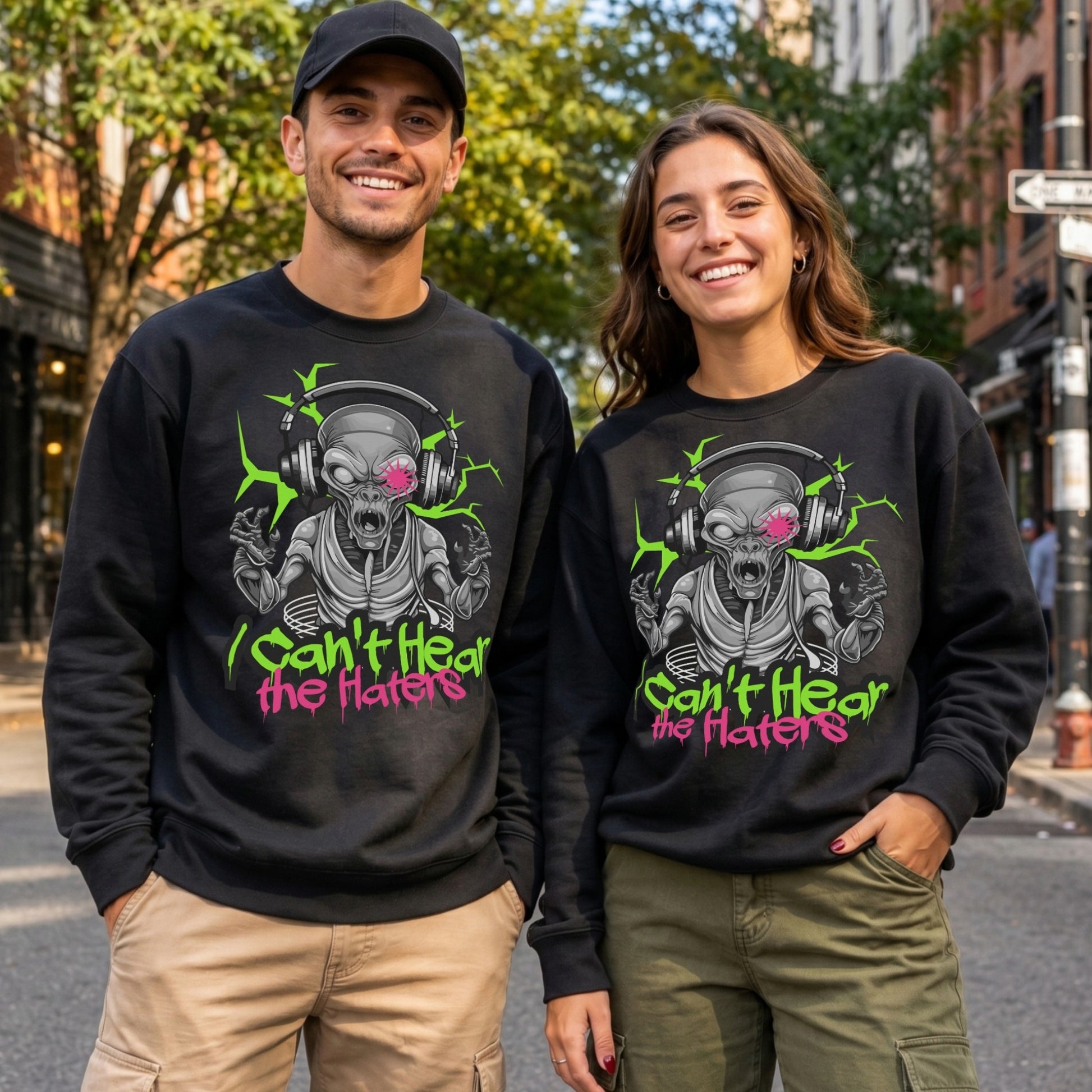 Male and female models wearing black I Can't Hear The Haters sweatshirts featuring a neon alien with headphones design, funny alien graphic sweatshirt and urban streetwear apparel.