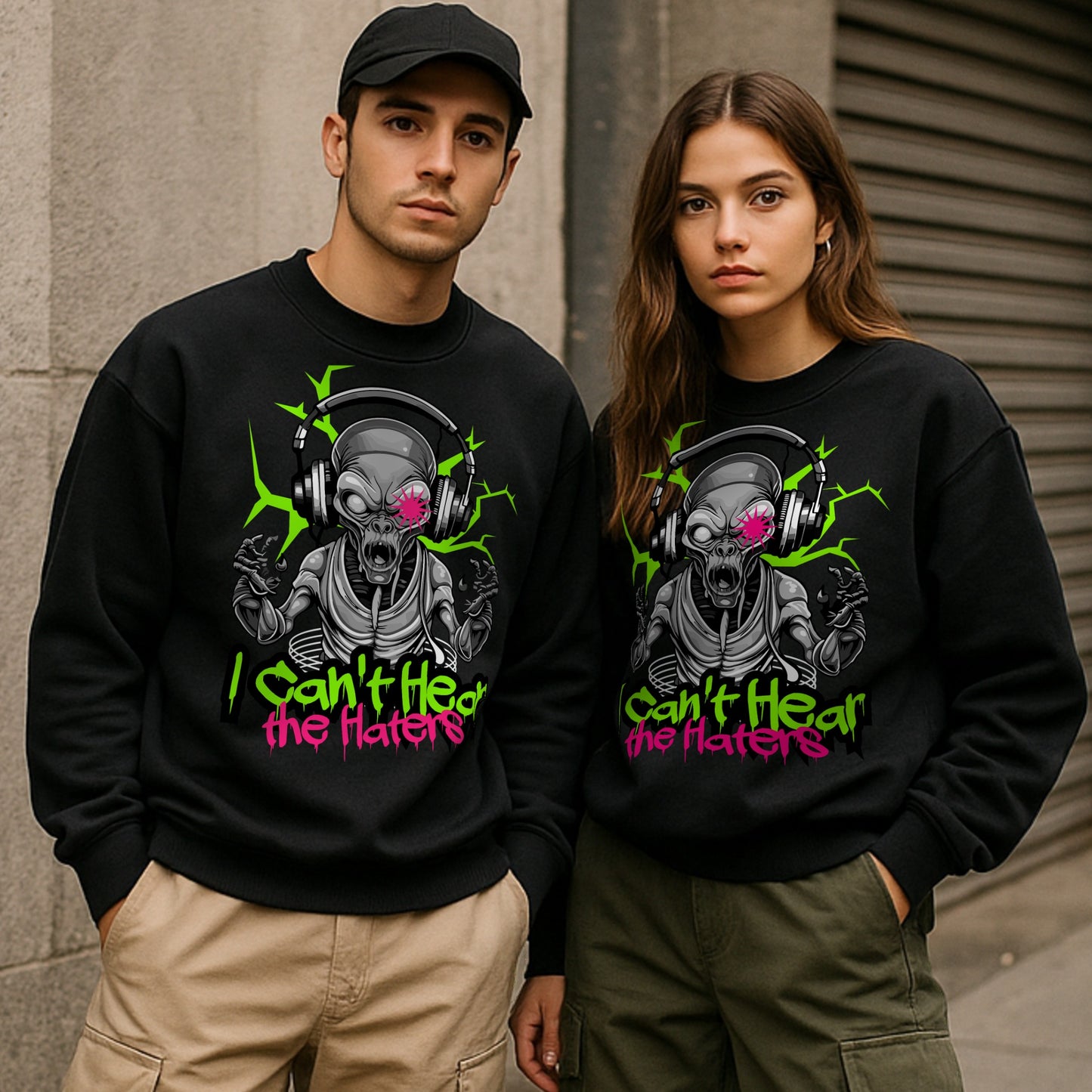 Two people wearing black sweatshirts with a alien graphic design and text that says I cant hear the haters