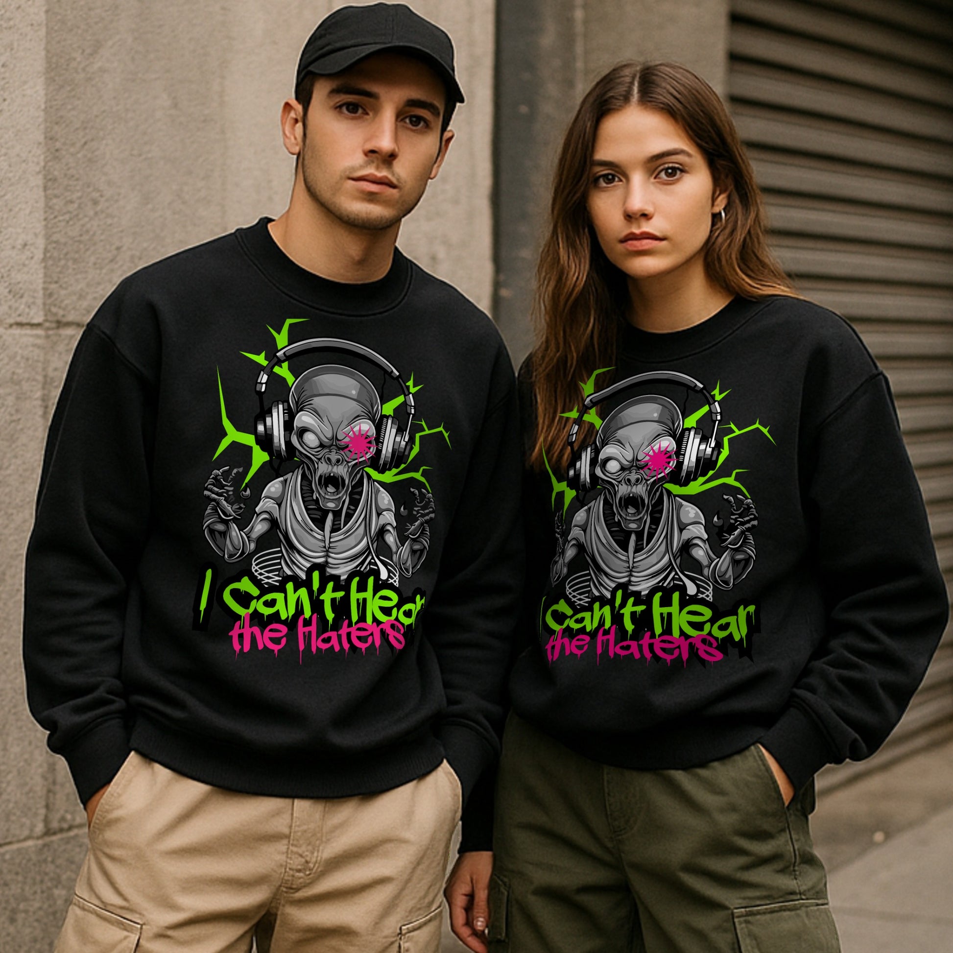 Two people wearing black sweatshirts with a alien graphic design and text that says I cant hear the haters
