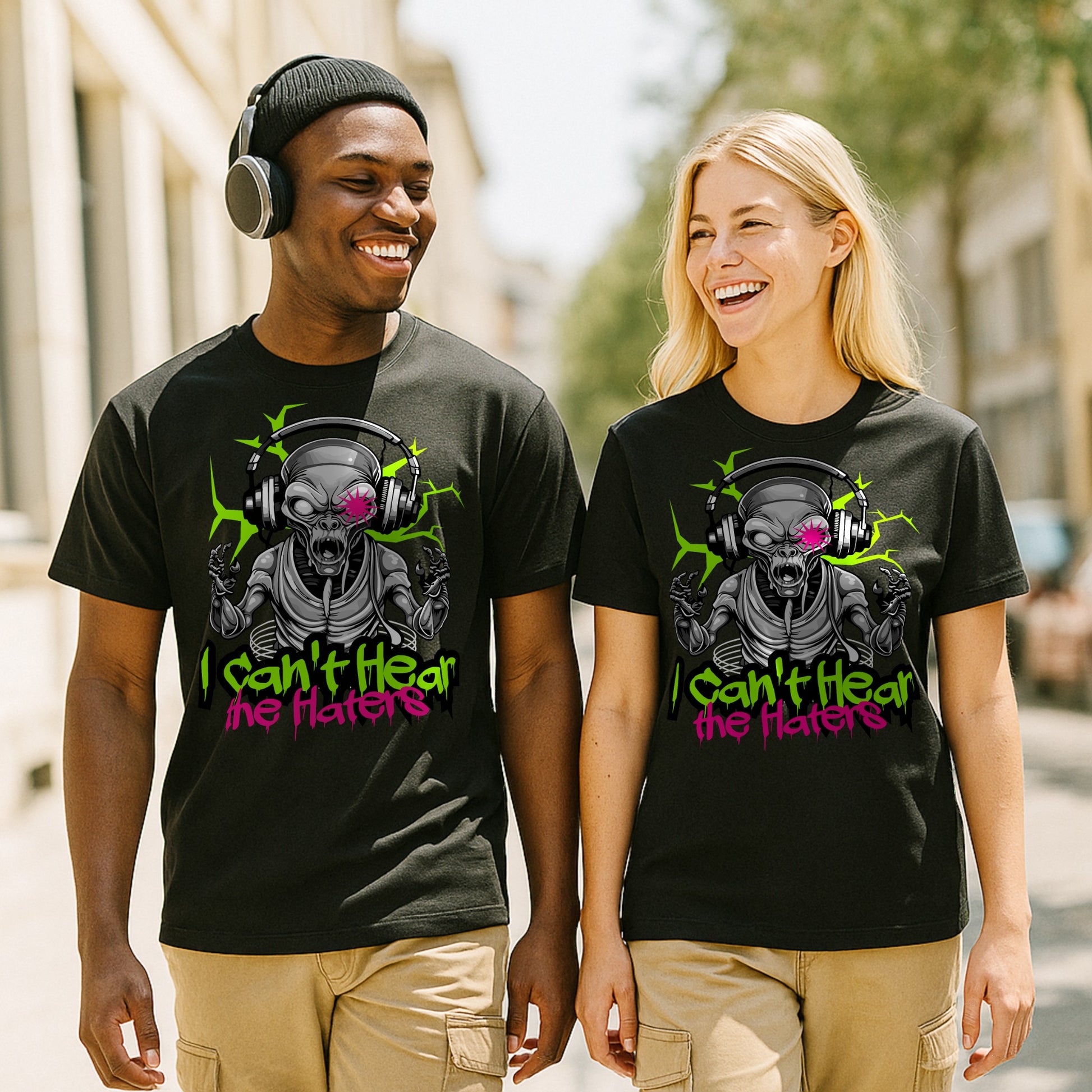 Two people wearing black t-shirts with a alien graphic design and text saying I cant hear  the haters, standing outdoors.