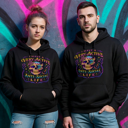 Two people wearing a black hoodie with “I Have a Very Active Anti-Social Life” print with a colourful skull, rose, and butterfly graphic — bold streetwear for cosy anti-social vibes.
