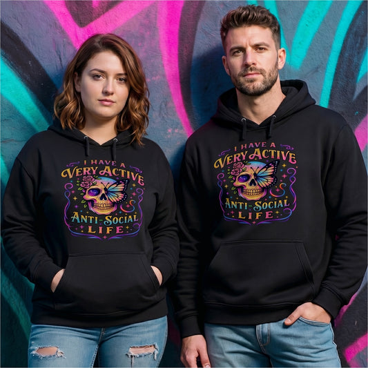 Male and female models wearing the I Have A Very Active Anti Social Life hoodie featuring a colourful neon sugar skull, butterfly, and floral graphic on black unisex hoodies against a vibrant graffiti wall.