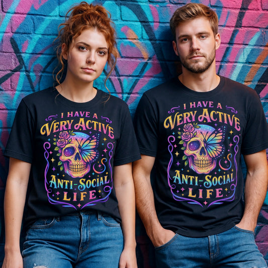 Male and female models wearing the I Have A Very Active Anti Social Life T-shirt featuring a colourful neon sugar skull, butterfly, and floral graphic on black unisex graphic tees against a vibrant graffiti wall.