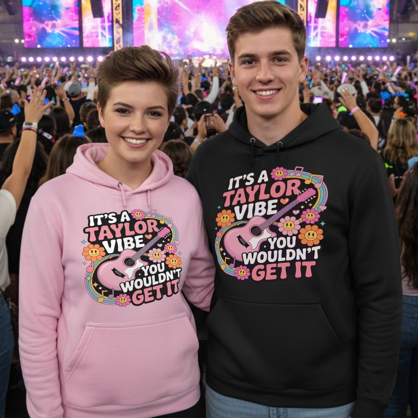 Lifestyle mockup of two fans wearing the It's A Taylor Vibe You Wouldn't Get It retro music fan hoodies in pink and black at a vibrant live concert with colourful stage lights and an excited crowd.