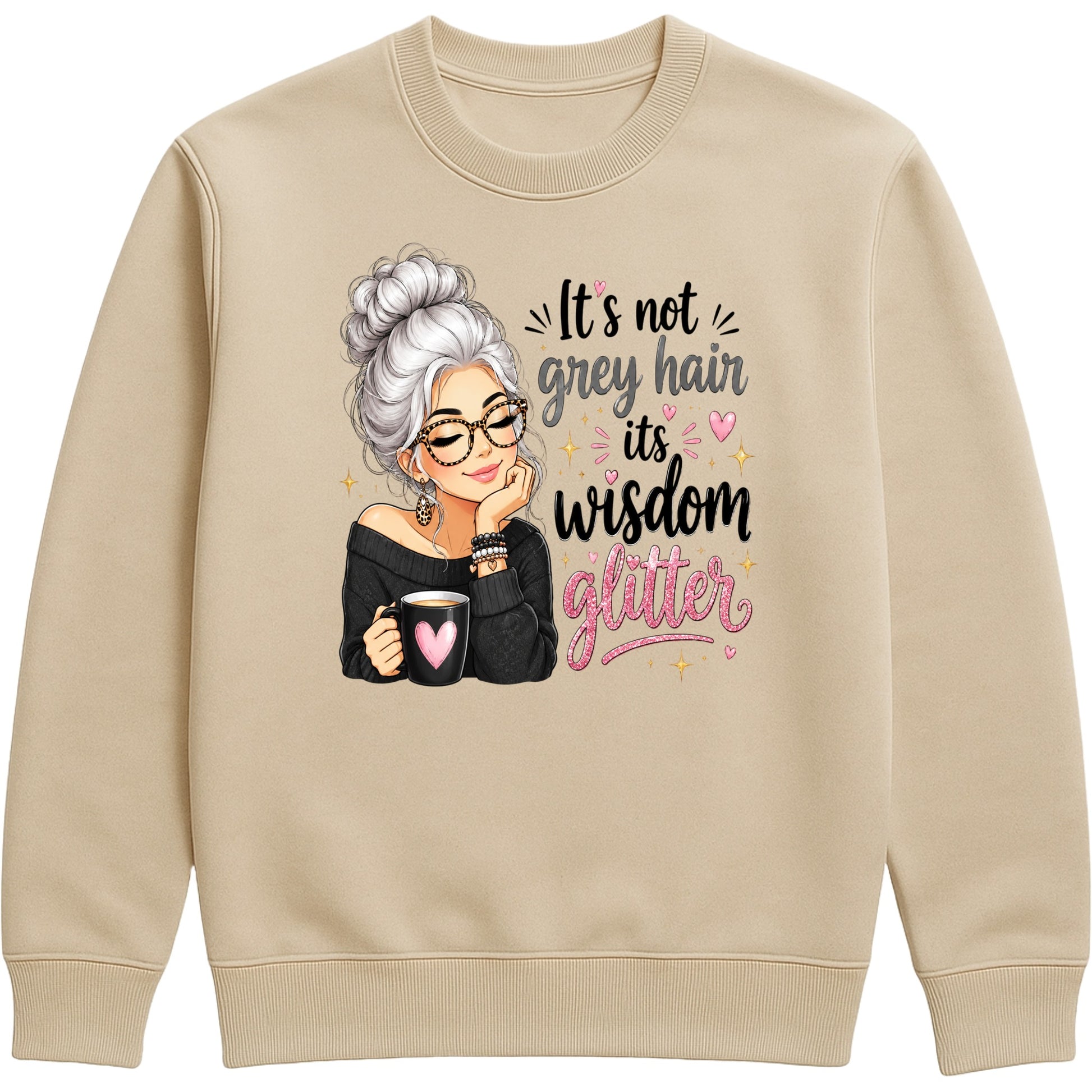 A nude colour crewneck sweatshirt featuring a graphic print of an elderly woman with grey hair, glasses, and a black top holding a mug with a pink heart, next to the text 'It's not grey hair, it's wisdom glitter' in black and pink lettering.