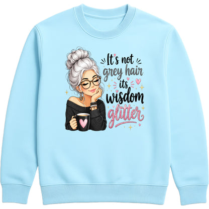 A sky blue crewneck sweatshirt featuring a graphic of an elderly woman with grey hair and glasses holding a mug, next to the text 'It's not grey hair it's wisdom glitter' in black and pink lettering.