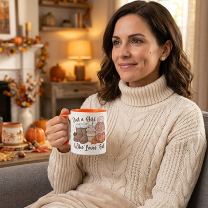 Woman relaxing at home holding the Just A Girl Who Loves Fall colour mug featuring autumn boots, a pumpkin spice latte, knitted beanie, colourful fall leaves and pumpkin artwork in a cosy autumn living room