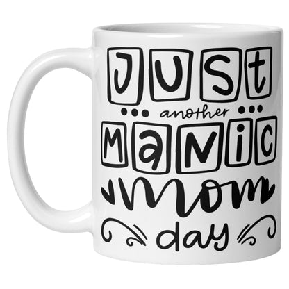 White coffee mug featuring the phrase "Just Another Manic Mom Day" in playful pink and black typography. Funny mom life coffee mug for busy mums, perfect as a mom gift, Mother's Day gift, or funny motherhood mug.