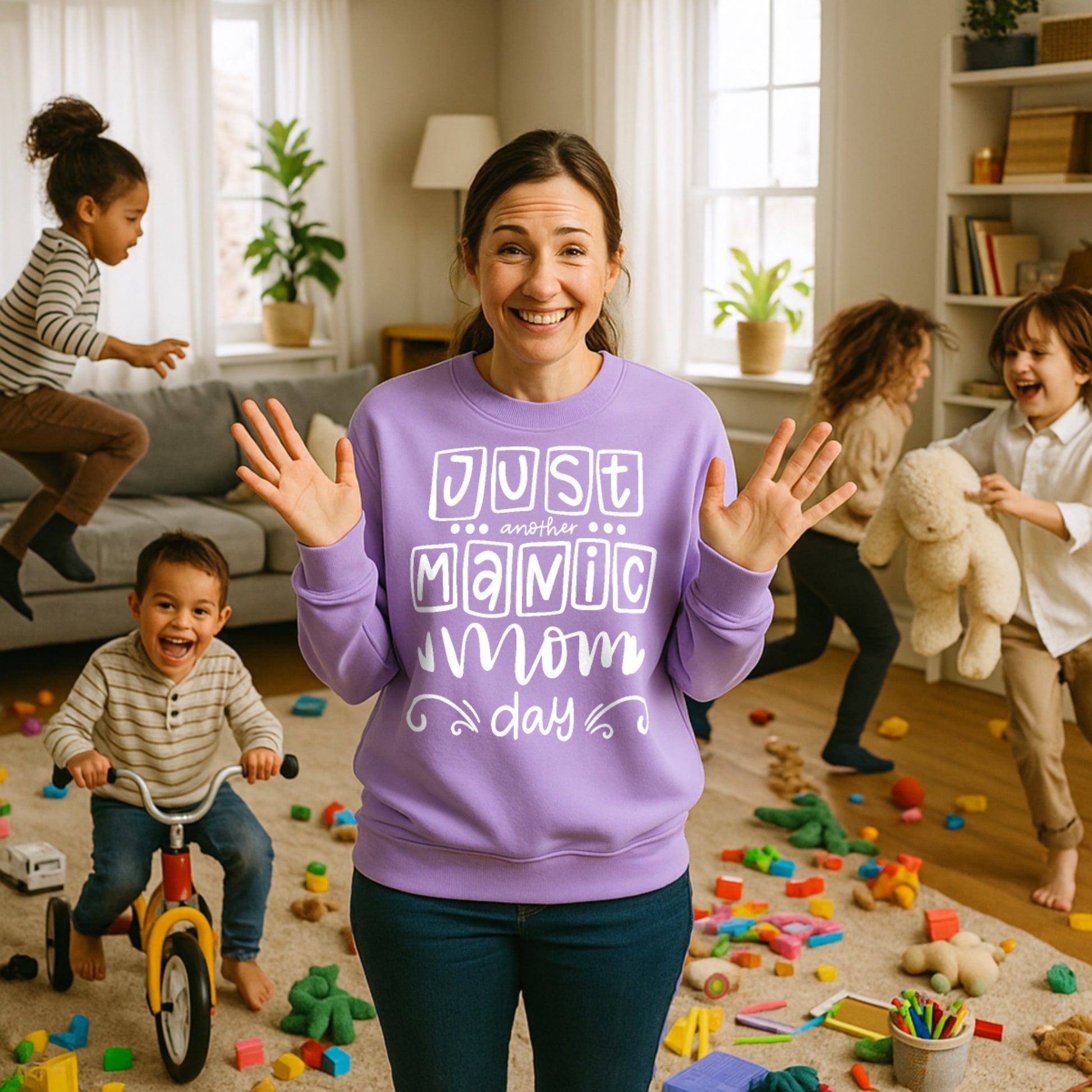Smiling mum wearing a digital lavender "Just Another Manic Mom Day" sweatshirt while surrounded by playful children and everyday family chaos. Funny mom life sweatshirt celebrating motherhood with humour, comfort, and style.