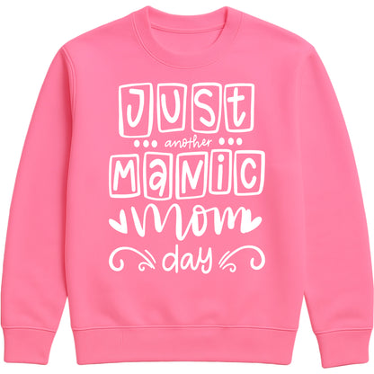 A candyfloss pink sweatshirt with 'Just Another Manic Mom Day' printed on the front, styled for casual everyday wear, perfect for moms balancing busy lives.