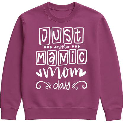 A plum sweatshirt with 'Just Another Manic Mom Day' printed on the front, styled for casual everyday wear, perfect for moms balancing busy lives.