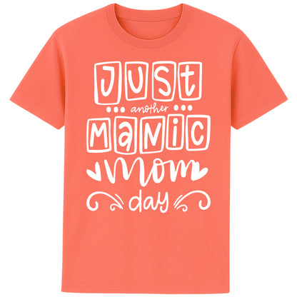 A bright fiesta colour t-shirt featuring the bold, playful phrase “Just Another Manic Mom Day” across the front in white lettering. The shirt is styled casually, perfect for everyday mom life, offering a comfortable fit ideal for running errands, school drop-offs, or relaxing at home. 