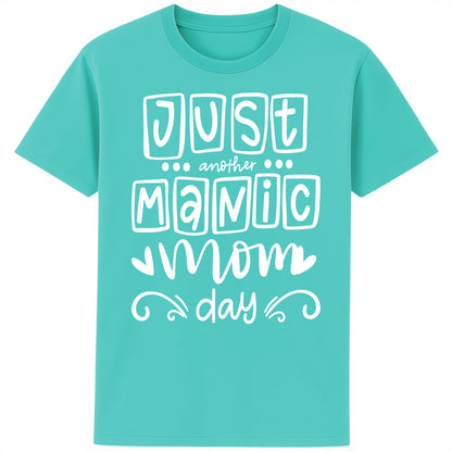 A bright pool blue t-shirt featuring the bold, playful phrase “Just Another Manic Mom Day” across the front in white lettering. The shirt is styled casually, perfect for everyday mom life, offering a comfortable fit ideal for running errands, school drop-offs, or relaxing at home. 