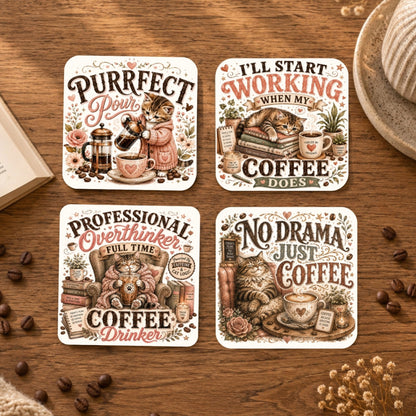 Four square coffee-themed coasters arranged on a wooden tabletop with scattered coffee beans and a cup in the background. The coasters feature whimsical illustrations of cats and coffee props with humorous quotes: 'Purrfect Pour,' 'I'll Start Working When My Coffee Does,' 'Professional Overthinker Full Time Coffee Drinker,' and 'No Drama Just Coffee.
