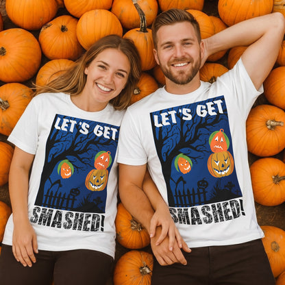 Smiling couple wearing matching white Let's Get Smashed Halloween T-shirts while relaxing in a pumpkin patch. Funny Halloween drinking shirts featuring stacked jack o' lantern pumpkins, perfect for Halloween parties, bar crawls, and spooky season.