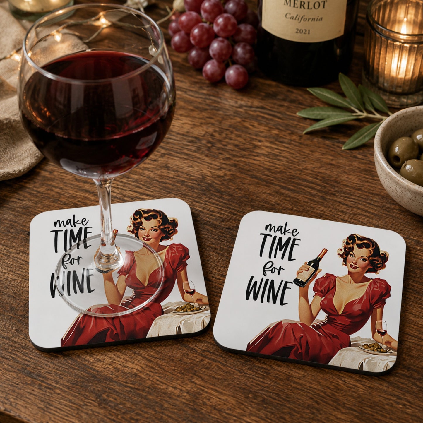Lifestyle mockup of the Make Time For Wine retro coaster with a glass of red wine resting on one coaster and a second matching coaster displayed beside it on a rustic wooden table with grapes, a wine bottle and cosy candlelight.