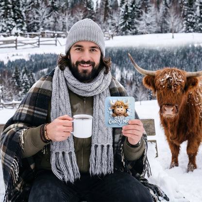 Lifestyle mockup of a man enjoying a hot drink in a snowy winter setting while holding a Merry Christmas Highland Cow Coaster, with a real Highland cow beside him, showcasing festive farmhouse Christmas décor.