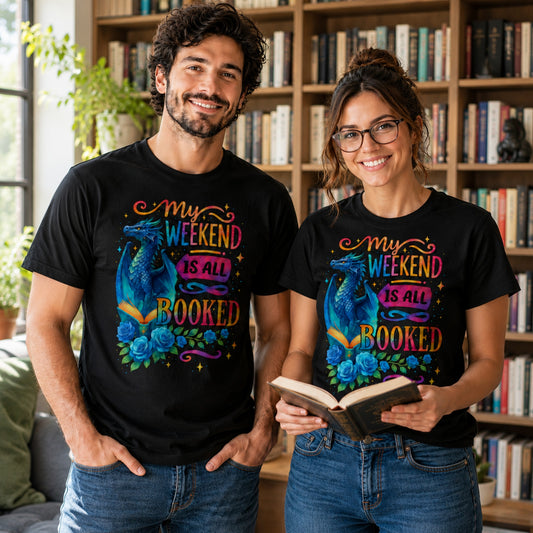 Man and woman wearing My Weekend Is All Booked book lover t-shirts featuring a blue fantasy dragon and enchanted book design while standing in a home library surrounded by bookshelves.