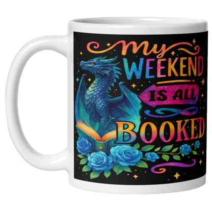 My Weekend Is All Booked coffee mug featuring a blue fantasy dragon, enchanted open book, colourful roses, and magical book lover artwork for readers and fantasy fans.