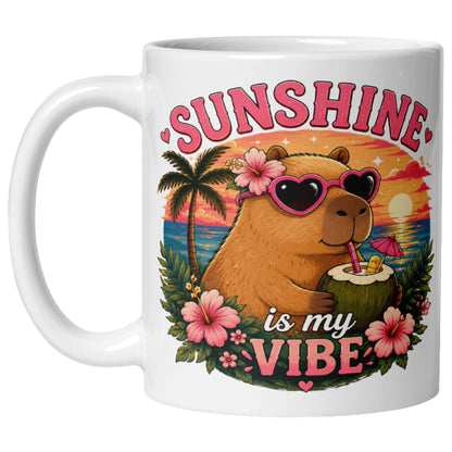 Sunshine Is My Vibe Capybara Mug featuring a cute capybara wearing heart-shaped sunglasses, relaxing with a coconut drink on a tropical beach at sunset.