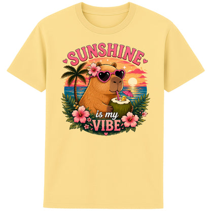 Yellow Sunshine Is My Vibe Capybara T-Shirt featuring a cute capybara wearing heart-shaped sunglasses, holding a coconut drink with tropical flowers, palm trees and a colourful summer beach sunset graphic.